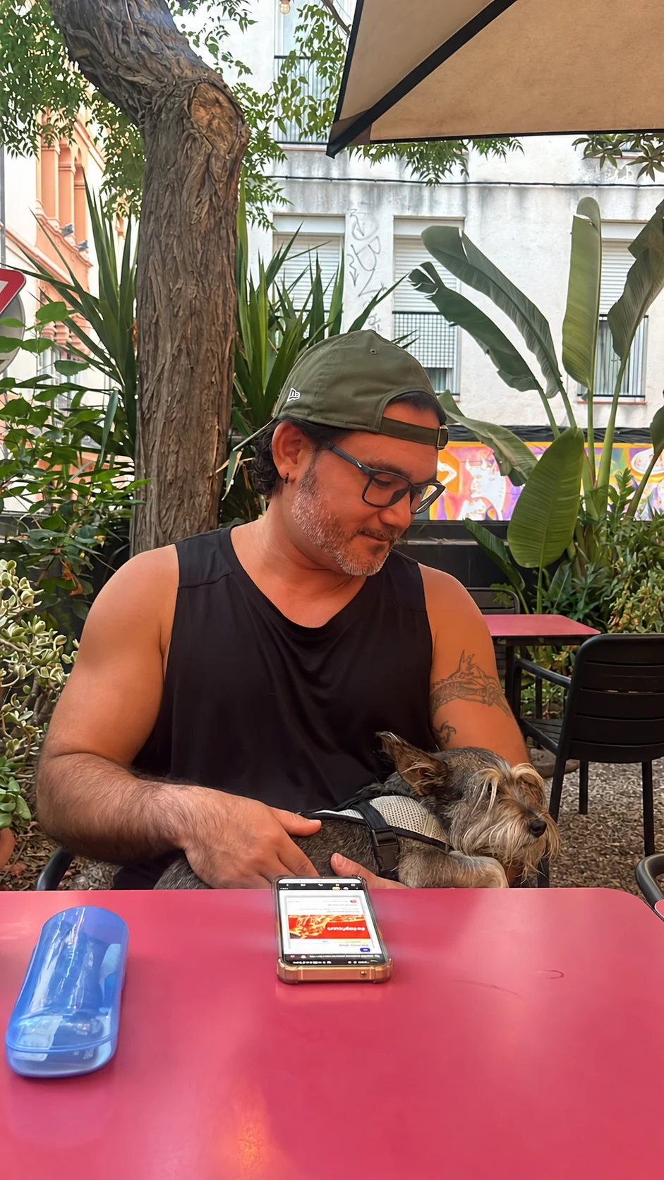 Alex holding his dog Cori on his lap at an outdoor café